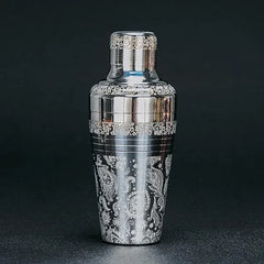 Shaker cocktail argenté gravé, mis en valeur sur fond sombre