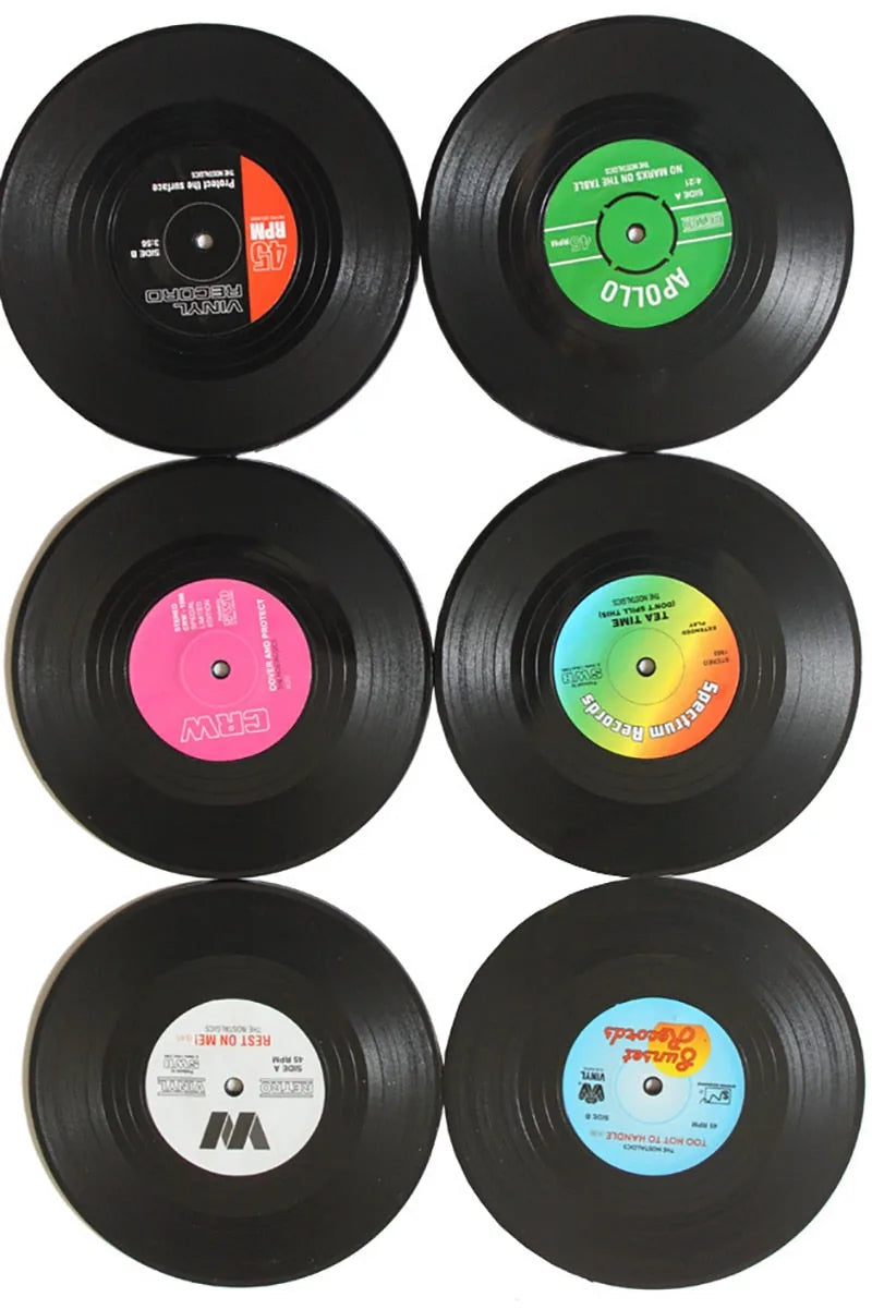 Collection de six sous-verres disques vinyles aux étiquettes multicolores différentes, vus de dessus sur fond blanc.