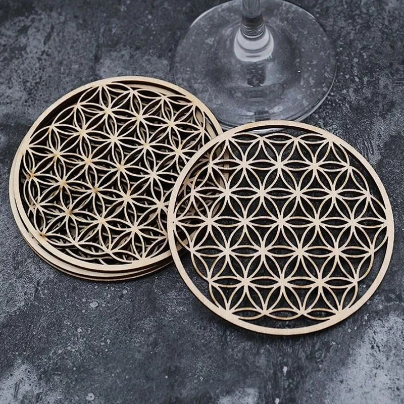 Lot de cinq sous-verres en bois motif Fleur de Vie empilés, avec un verre à pied posé sur le dessus.