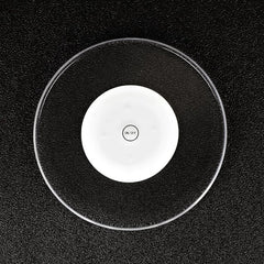 Gros plan du sous-verre lumineux posé sur une surface noire texturée, mettant en valeur son disque translucide et son bouton central.