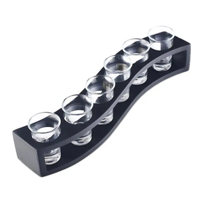 Support à shots en bois noir ondulé avec six verres à shot vides, présenté sur fond blanc.