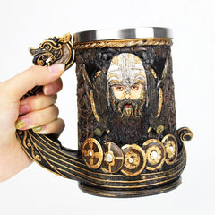 Gros plan sur la chope à bière Viking tenue en main, mettant en valeur le visage sculpté du guerrier et l'anse en forme de tête de dragon dorée