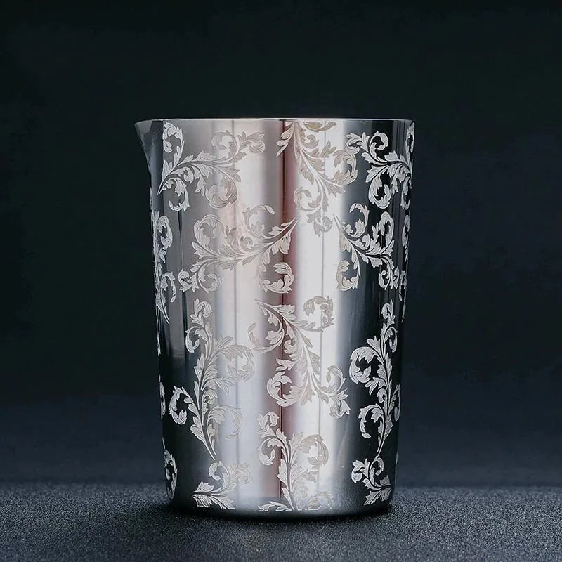 Verre à mélange en acier inoxydable au motif floral gravé, photographié en packshot élégant sur fond noir.