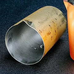 Gros plan sur le bec verseur et l'intérieur poli du verre à mélange doré, avec des gouttes d'eau visibles.
