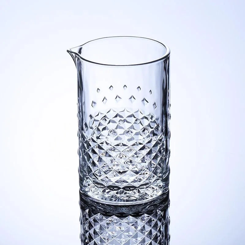 Verre à mélange pour cocktail vide, présenté sur fond dégradé bleu clair, motif diamant taillé en relief