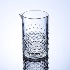 Verre à mélange pour cocktail vide, présenté sur fond dégradé bleu clair, motif diamant taillé en relief