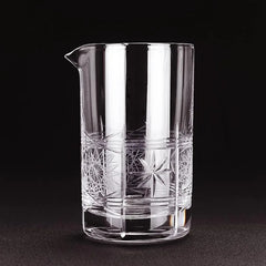 Gros plan sur le verre à mélange vintage vide, mettant en valeur les motifs de gravure étoilée taillés dans le cristal sur fond noir.