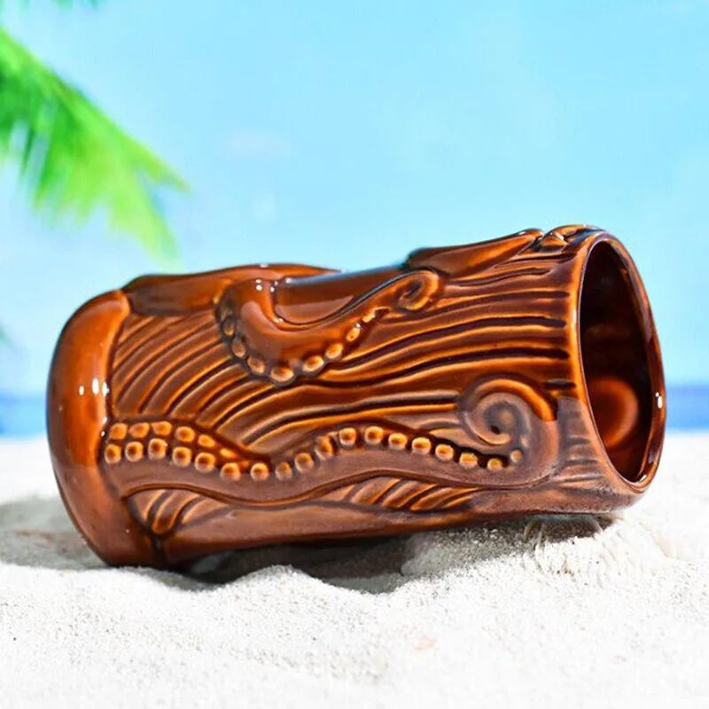Verre à rhum Tiki allongé sur le sable avec un ciel bleu et une feuille de palmier en arrière-plan