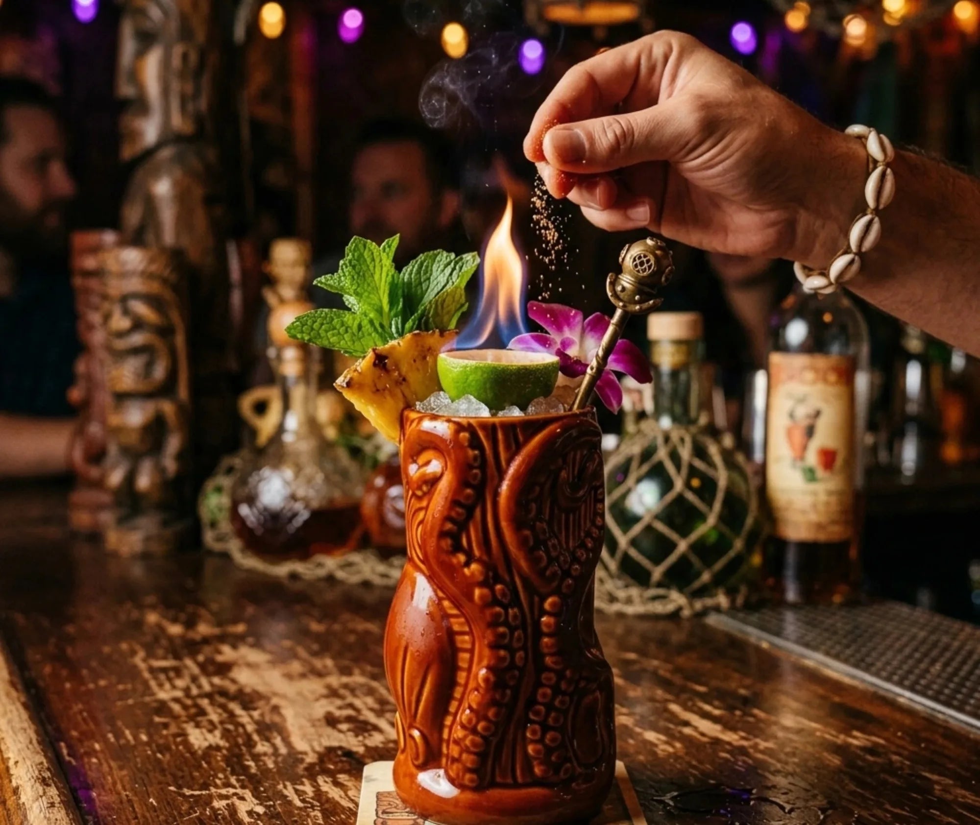 Cocktail tiki flambé servi dans le verre à rhum Tiki, décoré de menthe, ananas et citron vert, dans une ambiance de bar tropical