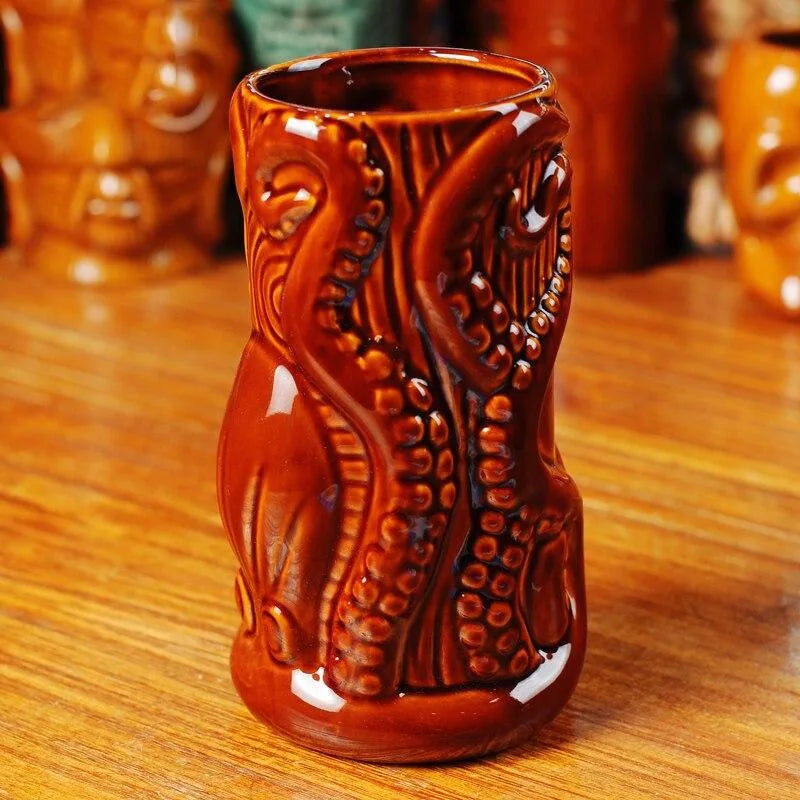 Verre à rhum Tiki posé sur un comptoir en bois, avec d'autres mugs tiki flous à l'arrière-plan