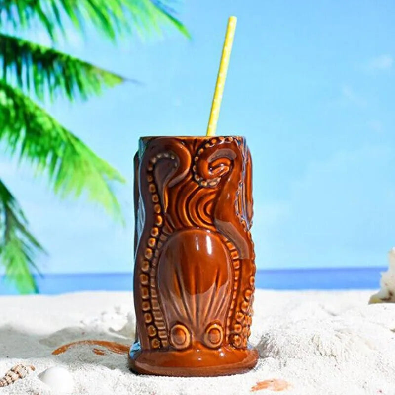Verre à rhum Tiki posé sur le sable avec une paille jaune, décor de plage tropicale en arrière-plan