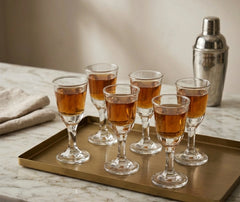 Set de 6 verres à shot pour rhum remplis et disposés sur un plateau doré, avec un shaker à cocktail argenté.