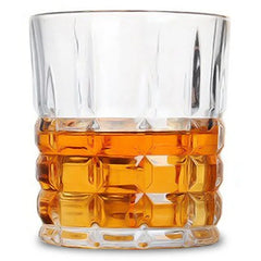 Verre à whisky de bar taillé rempli de whisky ambré, photographié en packshot sur fond blanc.