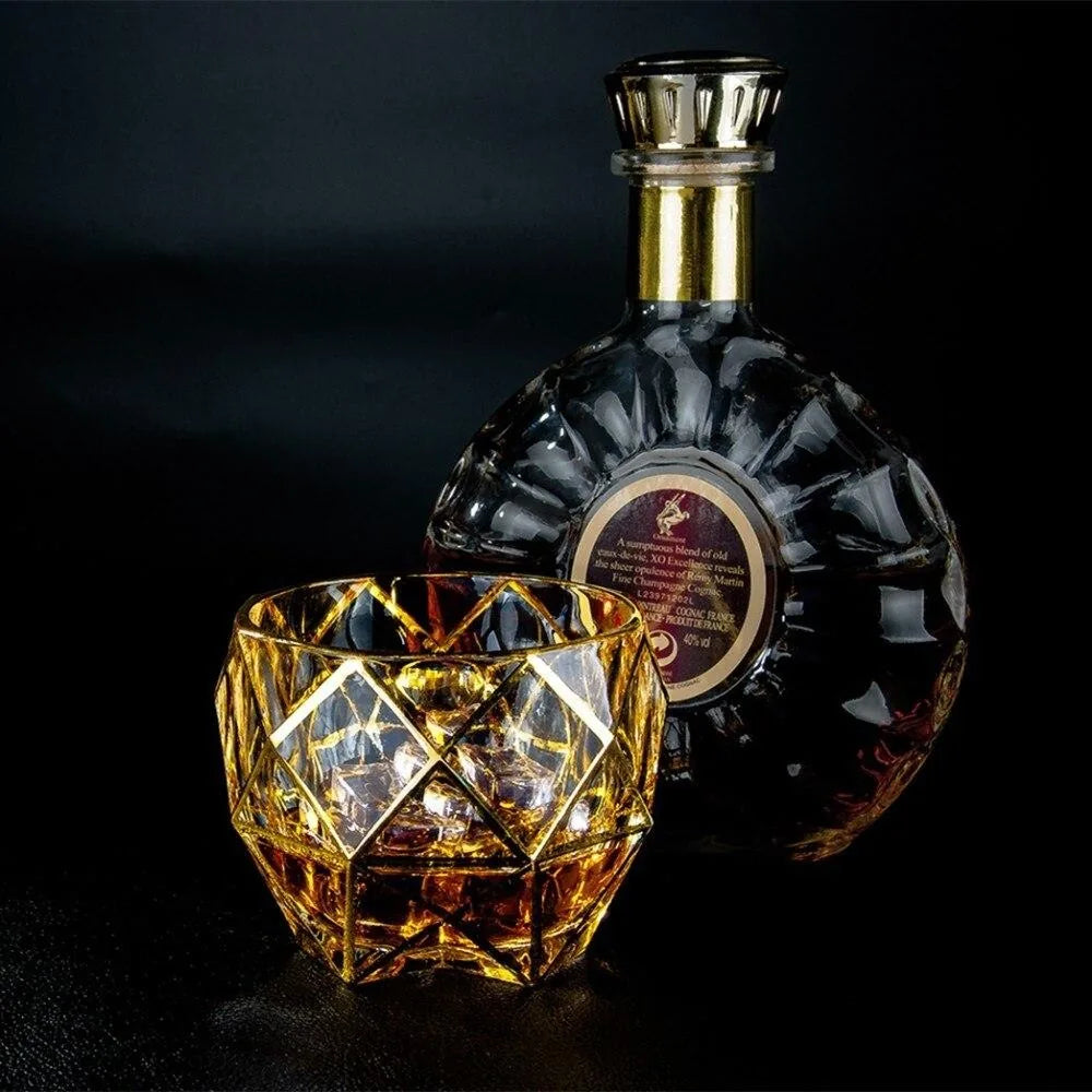 Verre à whisky de luxe posé à côté d'une bouteille de cognac Rémy Martin sur fond noir