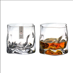 Duo de verres à whisky japonais côte à côte, l'un vide avec son étiquette d'origine, l'autre rempli de whisky ambré, sur fond blanc.