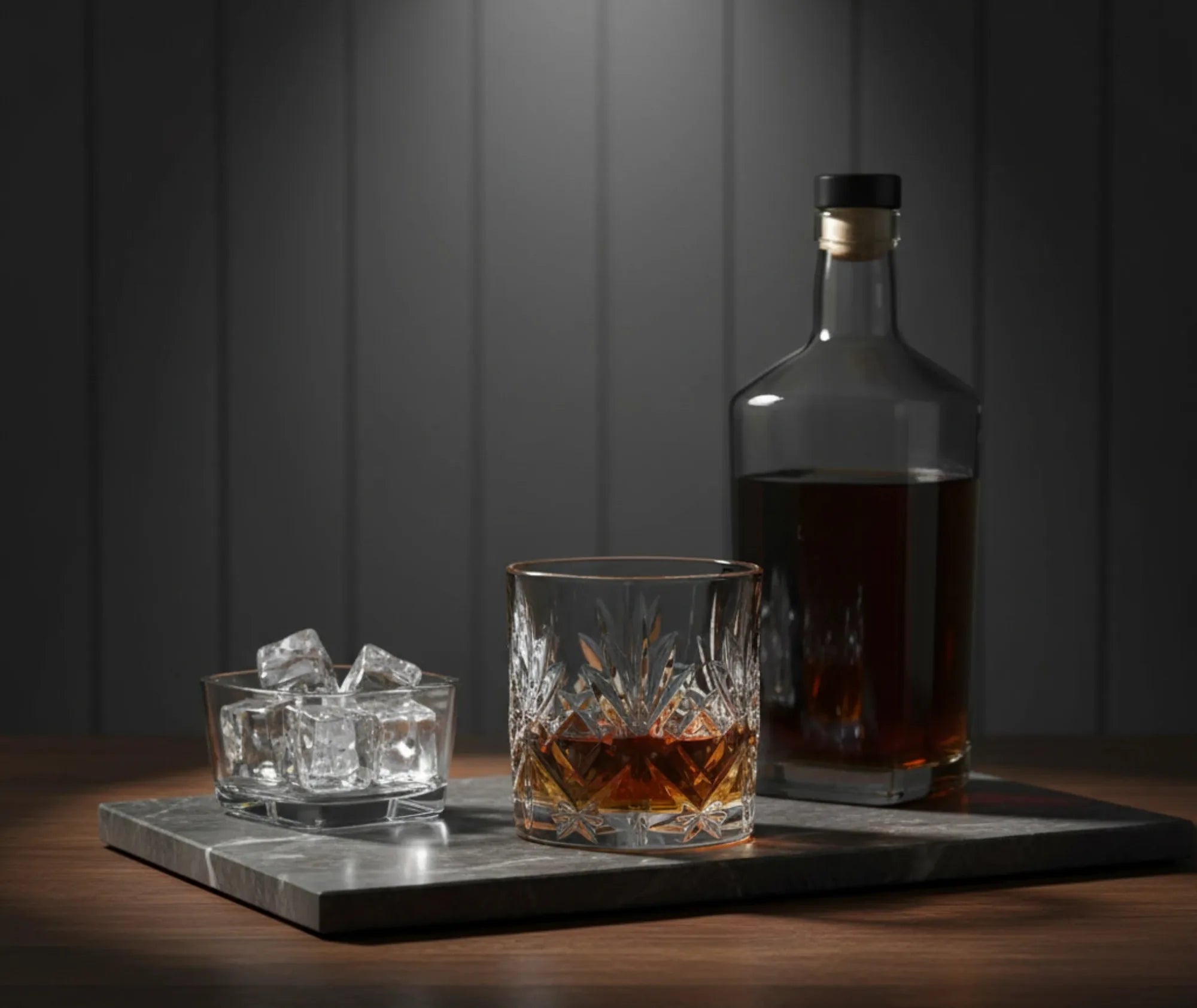 Verre à whisky vintage posé sur un plateau en marbre avec un bol de glaçons et une bouteille de whisky, ambiance bar tamisée.