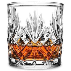 Verre à whisky vintage en cristal taillé rempli de whisky ambré, photographié sur fond blanc.