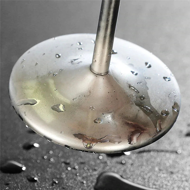 Gros plan sur le pied et le socle métallique du verre à cocktail, couvert de gouttes d'eau.