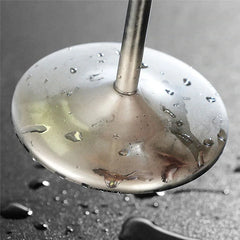 Gros plan sur le pied et le socle métallique du verre à cocktail, couvert de gouttes d'eau.