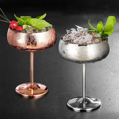Les deux coloris du verre à cocktail coupe, cuivre et argenté, placés côte à côte avec glaçons et menthe.