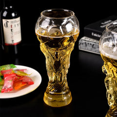 Deux verres Coupe du Monde remplis de bière ambrée sur une table noire avec bouteille de vin et amuse-bouches