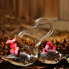 Duo de verres à cocktail cygne transparents vides, décorés de fleurs roses, posés en extérieur sur fond de feuilles d'automne