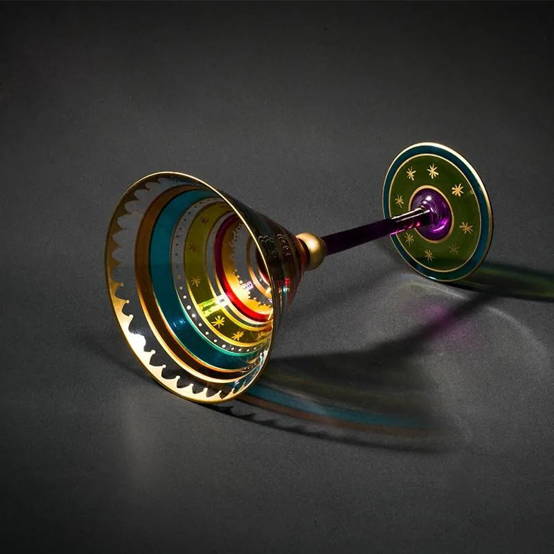 Verre à cocktail martini à dorures couché sur fond sombre dégradé avec reflets colorés