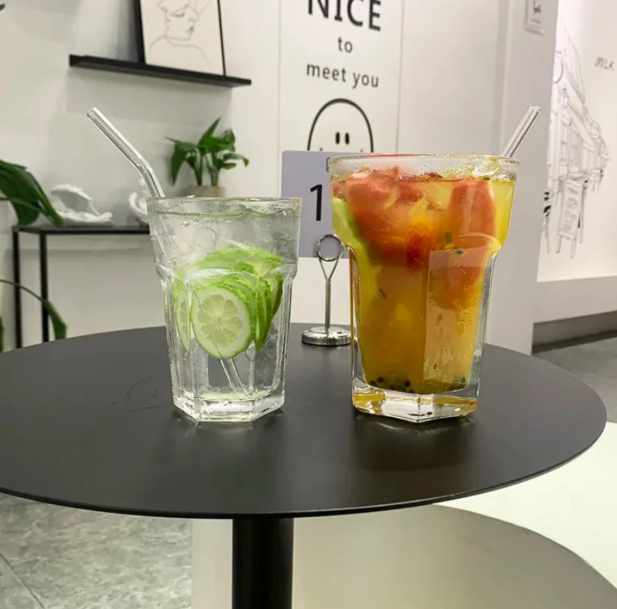 Deux verres à cocktail Mojito XL sur table ronde noire devant une enseigne « Nice to meet you », un verre citron vert concombre et un verre jus de fruits