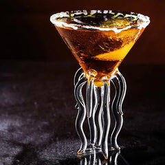 Verre à cocktail original rempli d'un cocktail ambré, mis en scène dans une ambiance sombre et élégante.