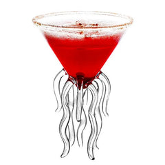 Verre à cocktail original en forme de méduse rempli d'un cocktail rouge, photographié sur fond blanc.
