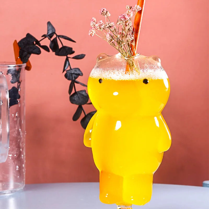 Verre ours avec cocktail jaune, paille et bouquet de fleurs séchées roses sur fond corail