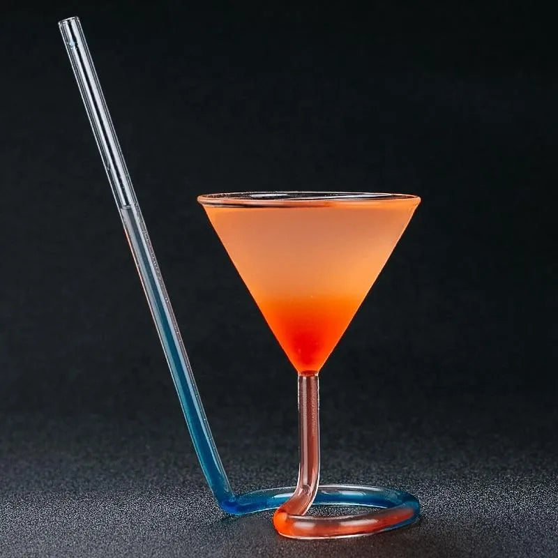 Verre à cocktail avec paille intégrée rouge, rempli d'un cocktail rouge glacé décoré de framboise et de menthe, posé sur un comptoir de bar