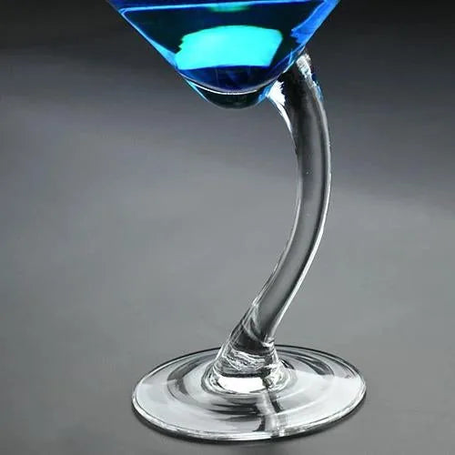 Gros plan incliné sur un verre à cocktail bleu avec un pied courbé en verre transparent.