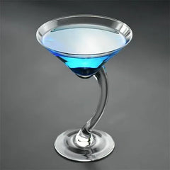 Verre à cocktail pied courbé rempli d'un cocktail bleu, avec un pied incurvé en verre transparent, sur fond gris.