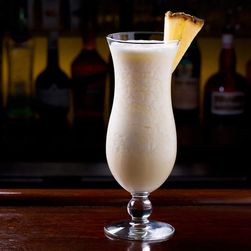 Piña Colada servie dans un verre sur un comptoir de bar, garnie d'ananas