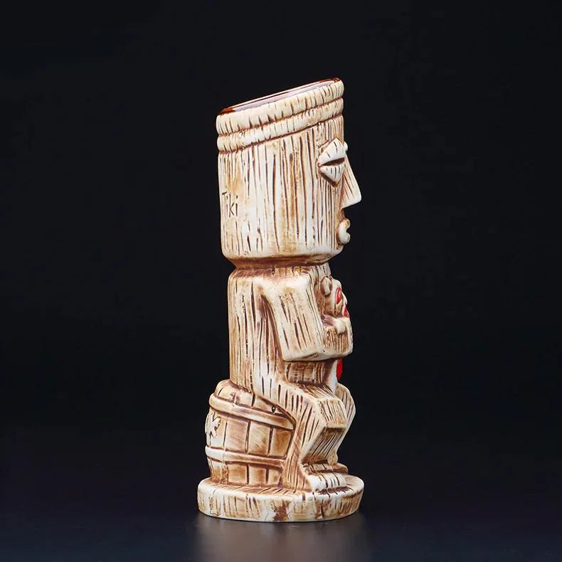 Vue de profil du verre à cocktail tiki en relief sculpté, sur fond noir, mettant en valeur les détails du visage et de la statuette.