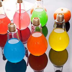 Plusieurs verres à cocktail en forme d'ampoule remplis de boissons colorées (rouge, rose, vert, bleu, orange, jaune) alignés sur une surface réfléchissante.