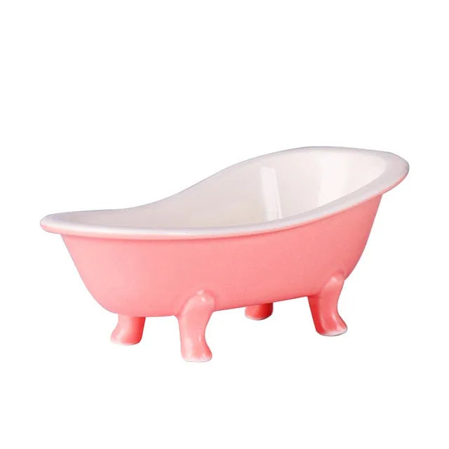 Verre en forme de baignoire rose posé sur fond blanc, vue de profil sur ses pieds ornementés