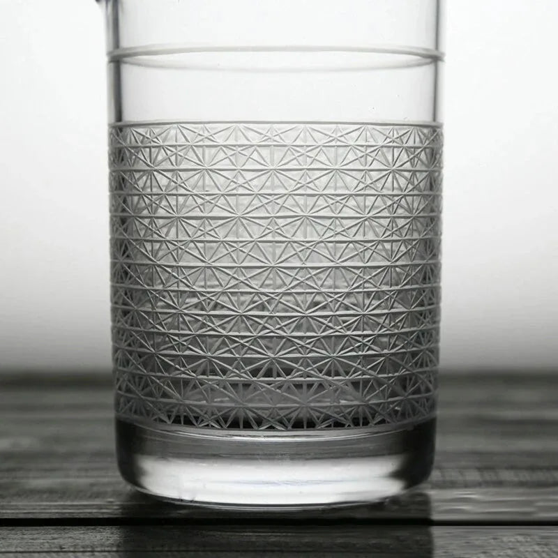 Gros plan sur le motif géométrique gravé à la main sur la paroi en verre, rempli d'eau.