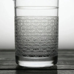 Gros plan sur le motif géométrique gravé à la main sur la paroi en verre, rempli d'eau.