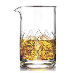 Verre mélangeur rempli de whisky ambré et de glaçons, vue packshot sur fond blanc