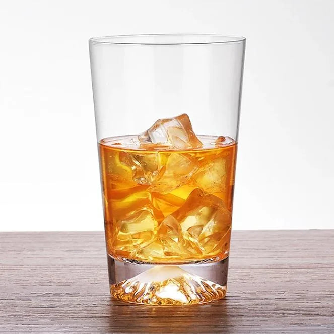Verre à montagne rempli de whisky ambré et de glaçons, photographié sur fond blanc