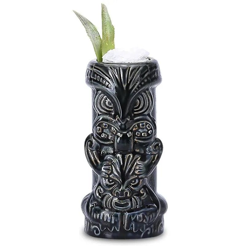 Verre à cocktail Tiki Dieu Noir rempli de glace pilée avec une garniture végétale sur fond blanc