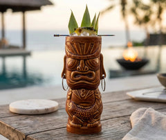 Verre tiki Tahiti marron posé sur une table en bois au bord d'une piscine au coucher du soleil