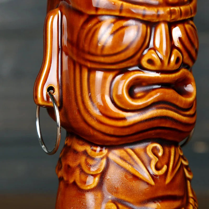 Gros plan sur le visage sculpté et l'anneau métallique du verre tiki Tahiti coloris marron cocotier