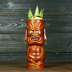 Verre à cocktail tiki Tahiti coloris marron cocotier vu de face sur fond bois sombre, garni de feuilles d'ananas