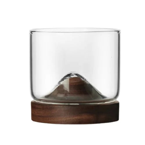 Verre à whisky avec socle en bois sculpté en forme de montagne, vide, présenté sur fond blanc
