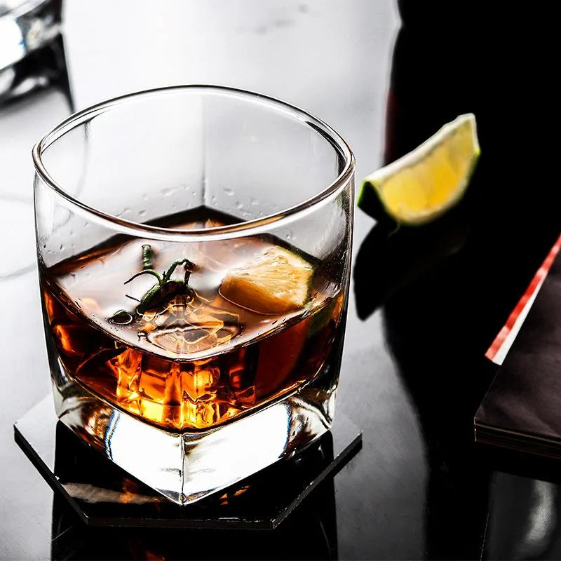 Verre à whisky fond épais garni de romarin et d'un quartier de citron vert, cocktail ambré vu de dessus