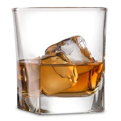 Verre à whisky fond épais rempli de glaçons et de whisky ambré, photographié sur fond blanc