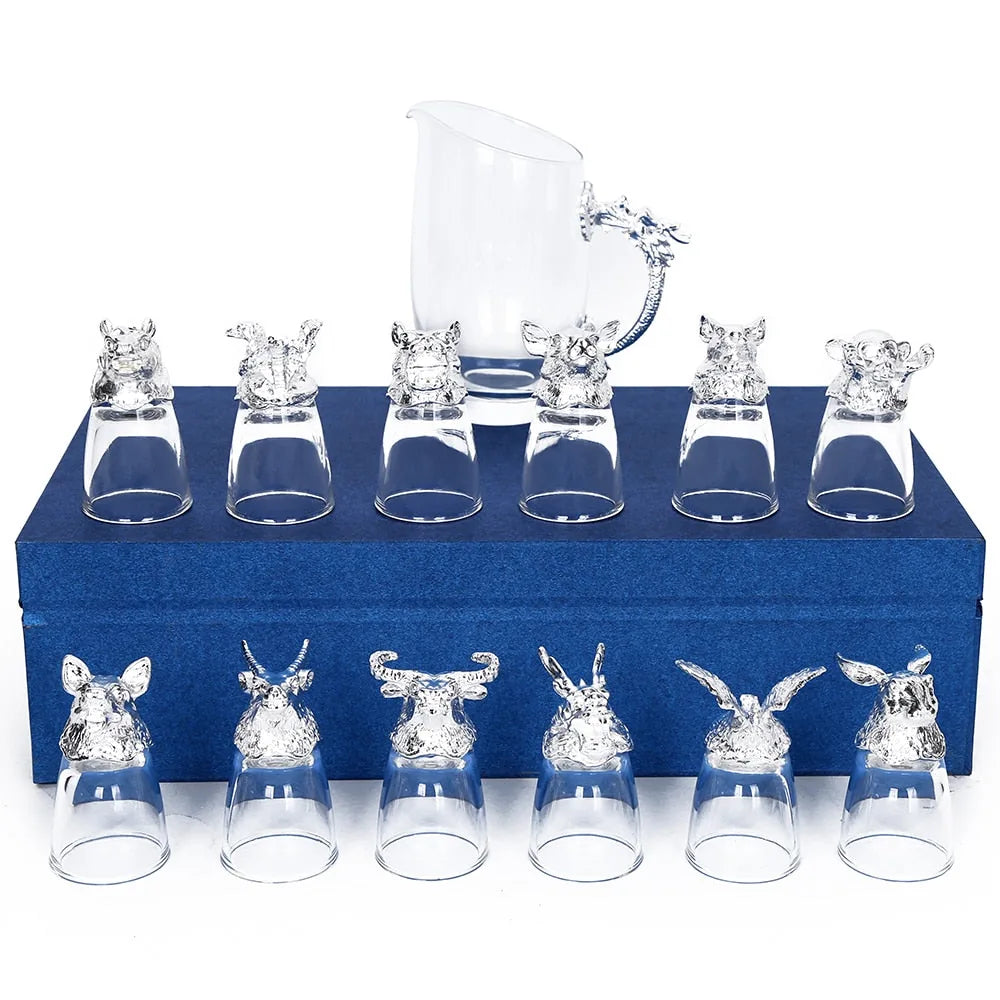 Ensemble complet de 12 verres à shot argentés et de la carafe assortie, disposés sur un coffret cadeau bleu fermé.